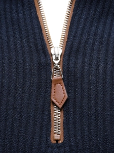 Detailed macro view of high-quality metal zipper and leather puller on ribbed knit sweater
