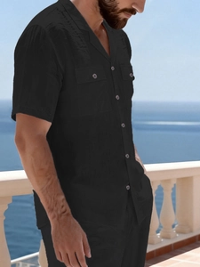 Detail of men's black linen shirt with Cuban collar and dual chest pockets on seaside