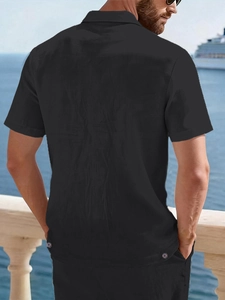 Rear view of black linen leisure shirt with collar detail on a sunny beach balcony