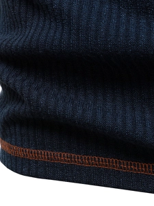 Macro detail of navy blue knit T-shirt hem with contrast orange stitching and ribbed fabric