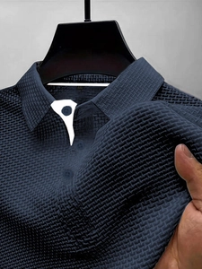 Detailed macro view of navy blue waffle knit fabric and shirt collar texture on polo