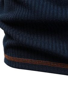 Detail of dark blue ribbed knit polo shirt hem featuring orange contrast stitching
