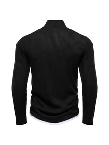 Close-up of black ribbed knit sweater featuring high neck and white layered hem detail