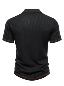 Macro detail of black polo shirt showing vertical knit texture and orange contrast stitching