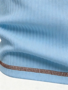 Macro detail of light blue ribbed knit fabric with contrasting dark brown stitching finish