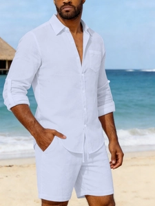 Close-up of men's white linen long-sleeve shirt and drawstring shorts on beach