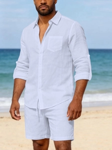 Men's white linen shirt set featuring a single chest pocket and rolled sleeves at the beach
