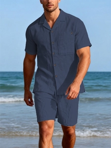 Detail of dark blue linen shirt and drawstring shorts set against a beach backdrop