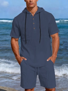 Detail of dark blue linen men's set featuring hooded shirt with wooden buttons and drawstring
