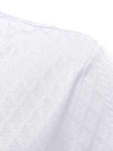 Vue détaillée du tissu du polo blanc montrant des textures florales jacquard complexes