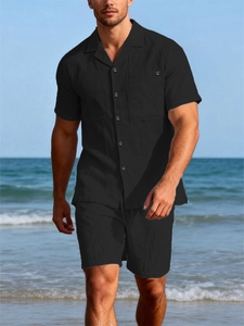 Detail of men's black linen shirt with chest pocket and matching drawstring shorts
