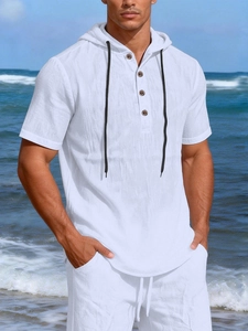 Detail of white linen hoodie shirt with wooden buttons and drawstring on a beach