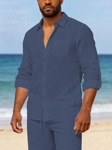 Detail of navy blue linen beach shirt showing chest pocket and roll-up sleeve buttons