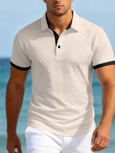 Détail du polo en maille crème avec texture en losanges et bords contrastés noirs