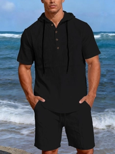 Detail view of men's black linen hoodie set with drawstrings and buttons on a beach