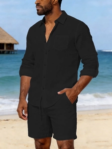 Detail of men's black linen button-down shirt and drawstring shorts on beach