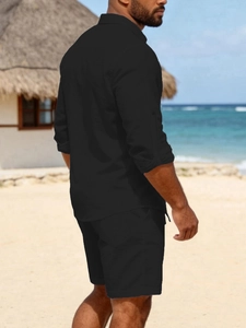 Close-up of men's black linen shirt and shorts set worn on a tropical beach setting