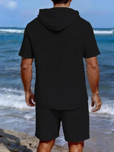 Rear view of men's casual black hooded linen set worn by a model on a sunny beach