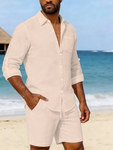 Detail of men's linen set featuring long-sleeved button shirt and shorts on a beach