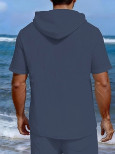 Rear view of a men's linen short-sleeved hooded t-shirt and shorts set on a beach