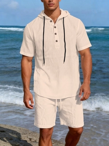 Detail of men's beige linen set featuring short sleeve hoodie and drawstring shorts at beach