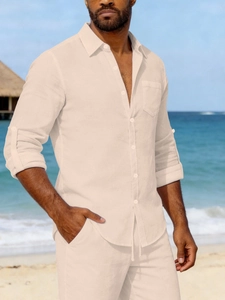 Detail view of beige linen shirt texture with chest pocket and lapel collar in a beach setting