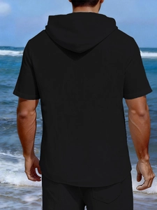 Back view of a casual black hooded short sleeve linen shirt on a scenic beach setting
