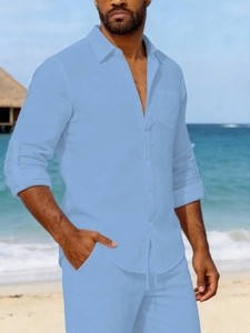 Detail of light blue linen shirt featuring sleeve tabs and textured pocket for beach vacations