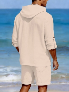 Détail d'un ensemble en lin beige pour homme avec chemise à capuche sur fond de plage