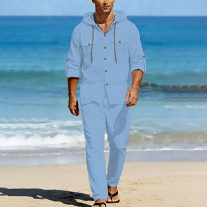 Detail of light blue linen men's set featuring hooded shirt and drawstring pants on beach