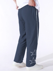 Dettaglio dei pantaloni sportivi blu navy con strisce laterali e stelle ricamate