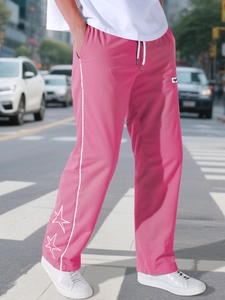 Dettaglio dei pantaloni sportivi rosa con ricamo a stelle bianche e strisce