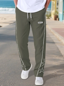 Dettaglio del ricamo a stella e strisce bianche sui pantaloni sportivi verde oliva