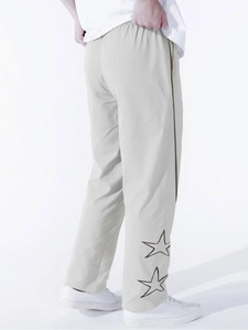 Dettaglio di stelle ricamate e strisce verticali su pantaloni sportivi grigi larghi