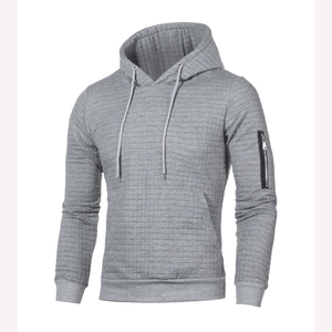 Détail d'un sweat à capuche gris pour hommes avec texture matelassée et poche zippée au bras