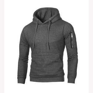 Détail du sweat à capuche matelassé gris foncé avec motif texturé et poche zippée manche