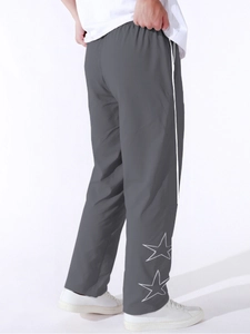 Dettaglio macro dei pantaloni sportivi grigi da uomo con strisce laterali e stelle
