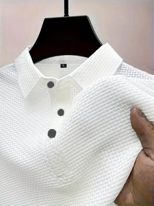 Close-up of white waffle texture polo shirt fabric with three grey buttons and collar