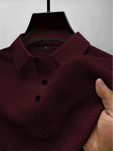 Detail of burgundy polo shirt with waffle texture fabric, turn-down collar and buttons