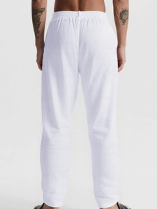 Detail view of the elastic waist and textured fabric on men's white linen casual pants