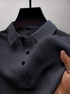 Detail shot of men's dark grey polo shirt showing waffle knit texture and button collar