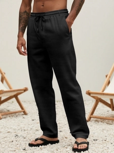 Detail of men's black linen pants featuring elastic drawstring waist and practical side pockets