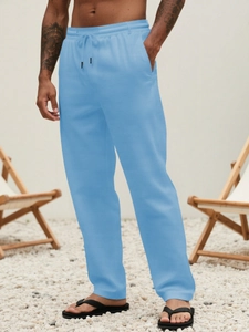 Detail of light blue linen pants featuring an elastic drawstring waist and side pockets