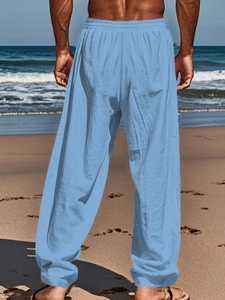Detail view of light blue linen blend breathable pants with elastic waistband on a beach