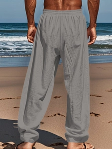 Detail view of grey linen hip hop pants with elastic waist on beach background