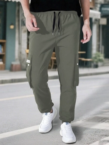 Detail of olive green cargo pants featuring drawstring waist and large flap utility pockets