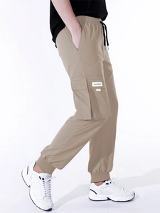 Detail view of khaki cargo pants with drawstring waist and large side flap pockets
