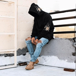 Détail de la broderie florale sur la manche et la capuche de ce sweat noir à capuche