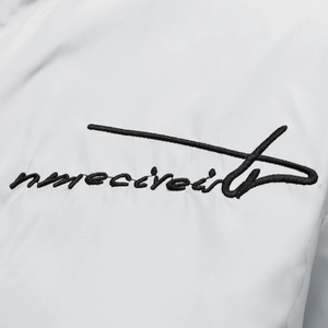 Close-up of black cursive embroidery detail on a white casual men's jacket fabric