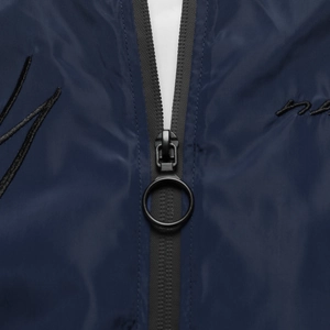 Close-up of a navy men jacket featuring a black zipper with a round pull and embroidery